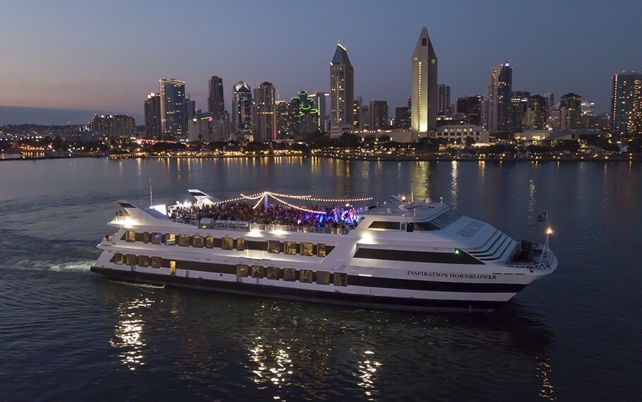 Yacht at night, lights from the city of San Diego in the background.