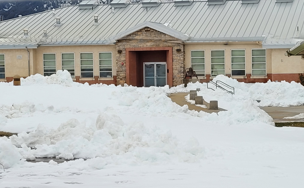 Snow covers the Julian High School campus. Mounds of snow in front of the building.
